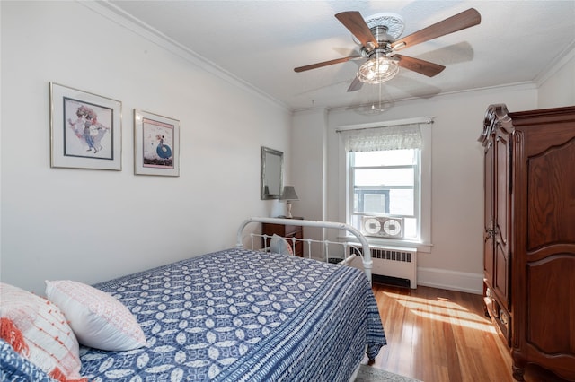 bedroom with radiator heating unit, light hardwood / wood-style flooring, ceiling fan, and ornamental molding