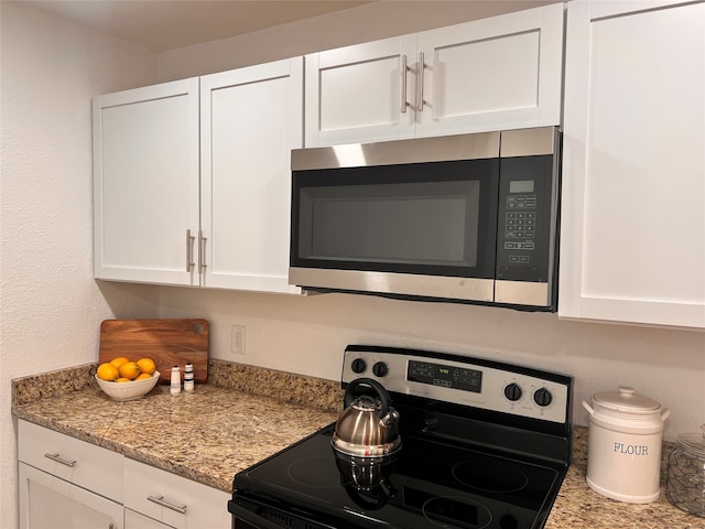 interior space featuring light stone countertops, appliances with stainless steel finishes, and white cabinetry