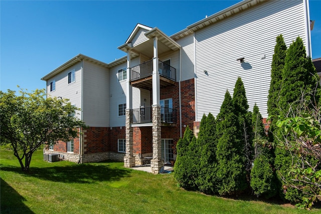 rear view of property with a balcony, a yard, and central AC unit