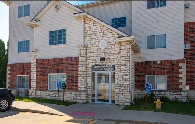 view of front of property featuring uncovered parking and stone siding