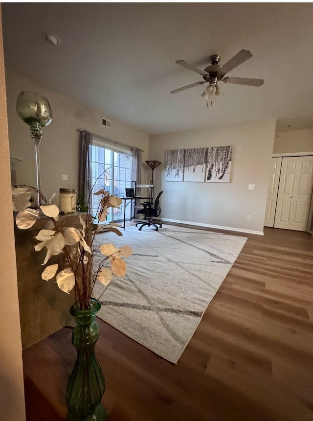 interior space featuring a ceiling fan, wood finished floors, visible vents, and baseboards