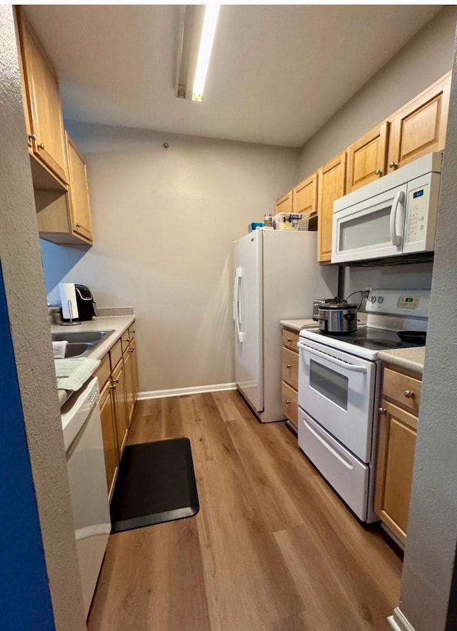 kitchen with light countertops, white appliances, light brown cabinets, and light wood-style floors