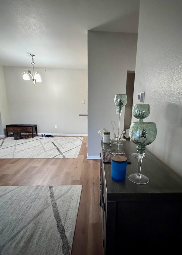 interior space featuring baseboards, a chandelier, and wood finished floors