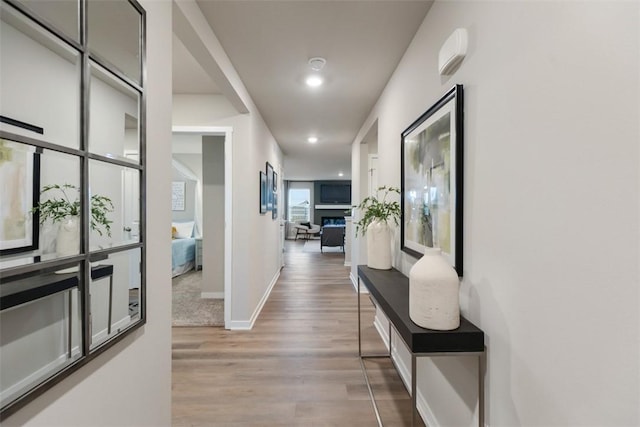 hall with baseboards, recessed lighting, and light wood-style floors