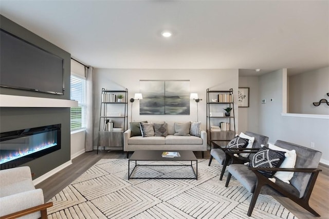 living room with a glass covered fireplace, baseboards, and wood finished floors