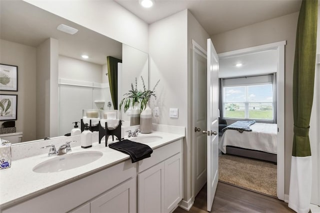 bathroom featuring double vanity, recessed lighting, a sink, and wood finished floors