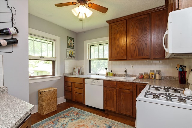 kitchen with dark wood-style flooring, tasteful backsplash, brown cabinets, a sink, and white appliances