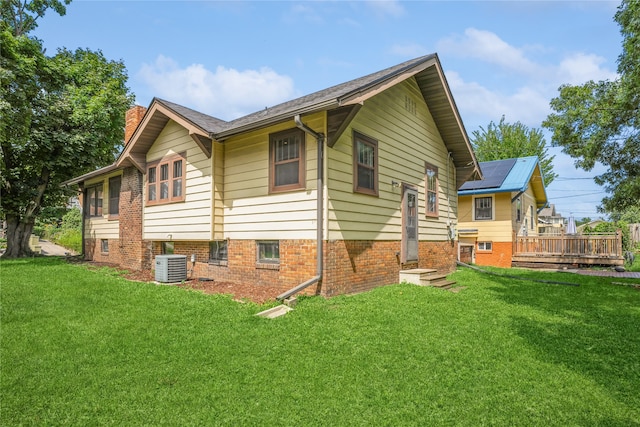 rear view of property with a yard, a deck, central AC, and a chimney