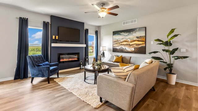 living room with ceiling fan, a fireplace, and hardwood / wood-style flooring