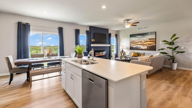 kitchen with visible vents, a kitchen island with sink, white cabinetry, a sink, and dishwasher