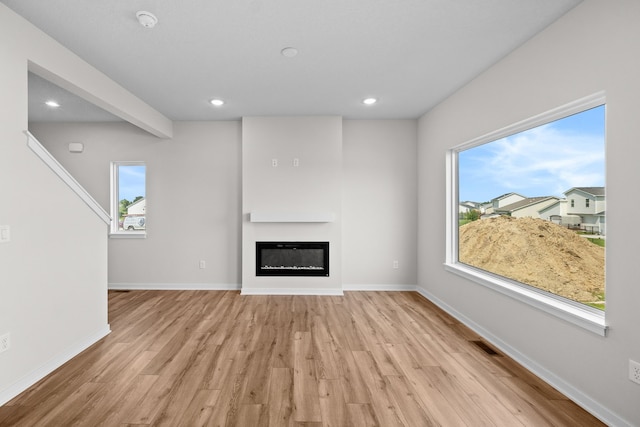 unfurnished living room featuring plenty of natural light and light hardwood / wood-style floors