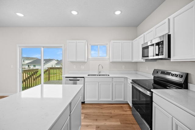 kitchen featuring appliances with stainless steel finishes, light wood-type flooring, sink, and white cabinets