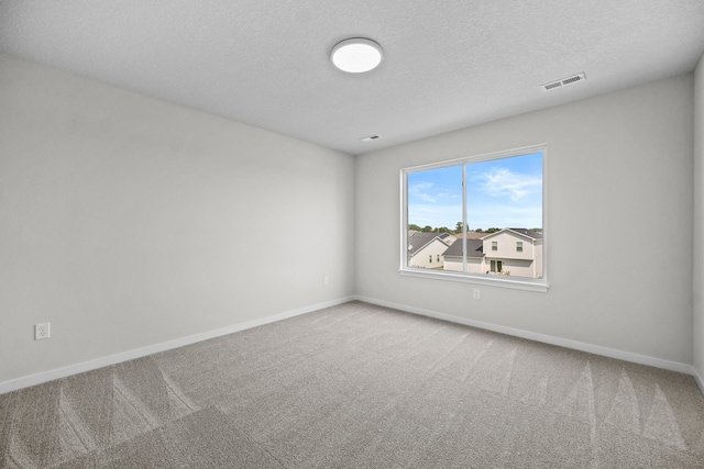 carpeted empty room featuring a textured ceiling