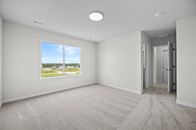 spare room with a textured ceiling and light carpet