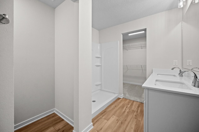 bathroom with vanity, a shower, a textured ceiling, and hardwood / wood-style flooring