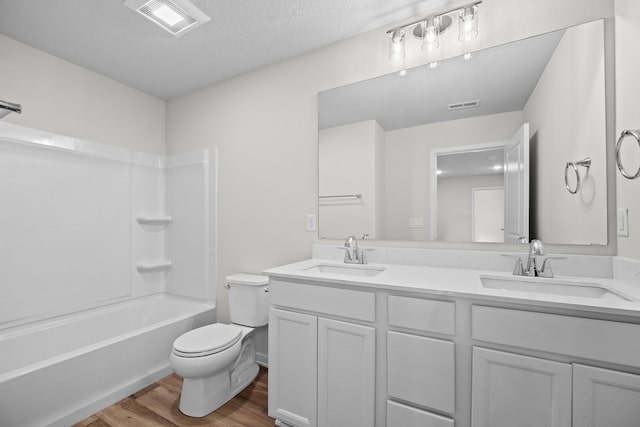 full bathroom featuring tub / shower combination, vanity, wood-type flooring, toilet, and a textured ceiling