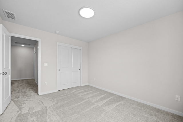 unfurnished bedroom with a closet and light colored carpet