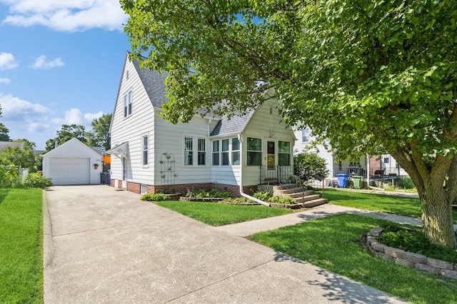 view of front of house featuring a garage, a front lawn, and an outbuilding