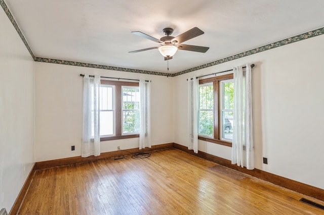 empty room featuring light wood-type flooring, a healthy amount of sunlight, and ceiling fan