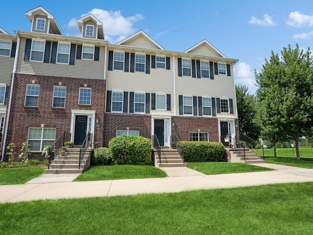 multi unit property featuring a front lawn and brick siding