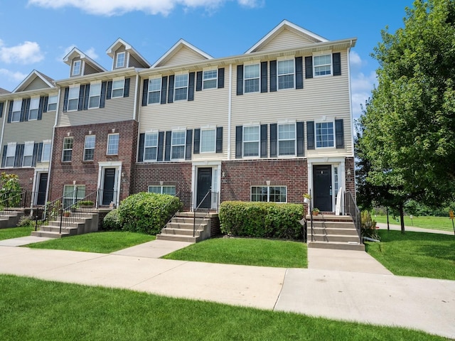 townhome / multi-family property with brick siding and a front lawn