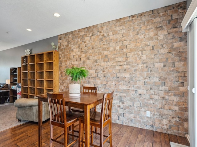 dining area featuring recessed lighting, wood-type flooring, and brick wall