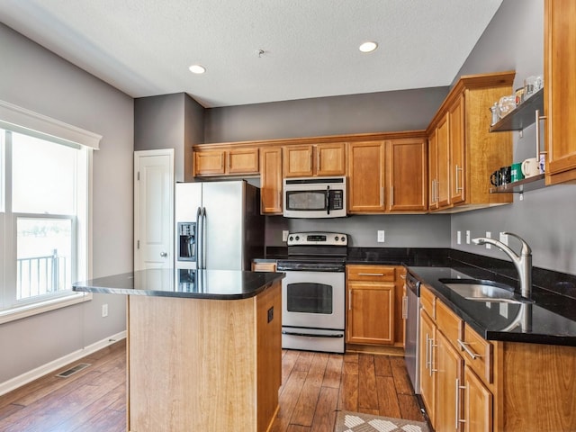 kitchen featuring visible vents, a sink, a center island, appliances with stainless steel finishes, and wood-type flooring