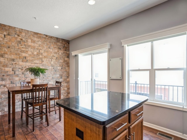 kitchen with visible vents, a center island, dark wood finished floors, brown cabinetry, and a textured ceiling