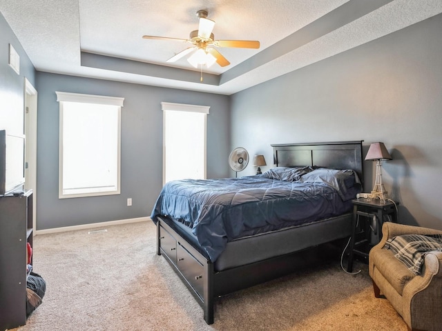 bedroom featuring a textured ceiling, carpet, a raised ceiling, and baseboards