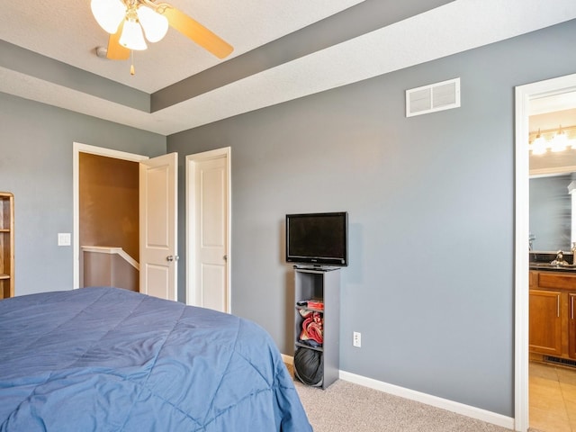 bedroom featuring visible vents, light carpet, ensuite bathroom, a sink, and baseboards