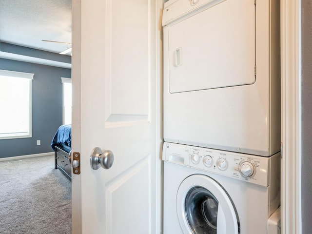 clothes washing area with laundry area, carpet flooring, baseboards, and stacked washer / drying machine