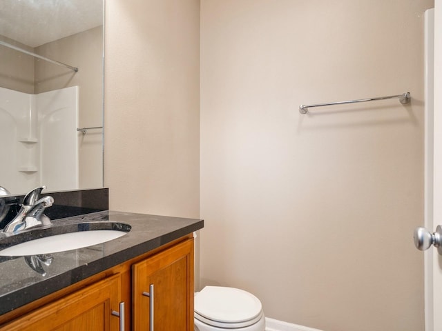 bathroom with baseboards, toilet, walk in shower, and vanity