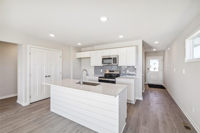 910 Willow Valley Dr, Norwalk, IA 50211 - kitchen with appliances with stainless steel finishes, a sink, white cabinets, light wood finished floors, and recessed lighting