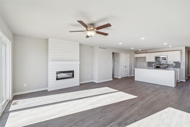 unfurnished living room featuring a fireplace, wood-type flooring, ceiling fan, and sink