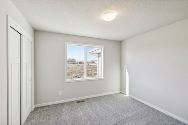 unfurnished bedroom with carpet flooring, a textured ceiling, and a closet