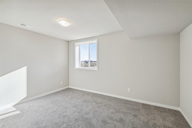 carpeted empty room featuring a textured ceiling