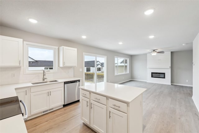 kitchen with stainless steel appliances, a fireplace, sink, and light hardwood / wood-style flooring