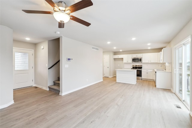 kitchen featuring stainless steel appliances, white cabinetry, a wealth of natural light, and light hardwood / wood-style flooring