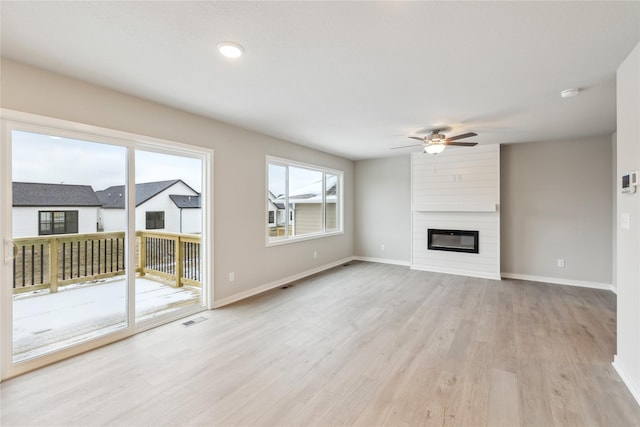 unfurnished living room featuring ceiling fan, light wood-type flooring, and a fireplace