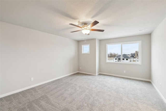 unfurnished room featuring a textured ceiling, ceiling fan, and light colored carpet