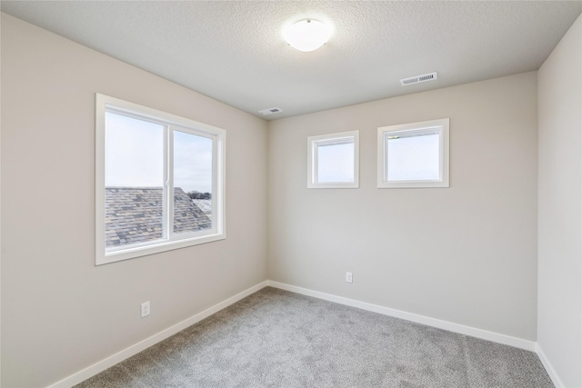 carpeted empty room with a textured ceiling