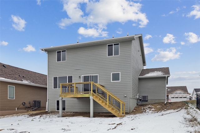 snow covered rear of property with central AC unit and a wooden deck