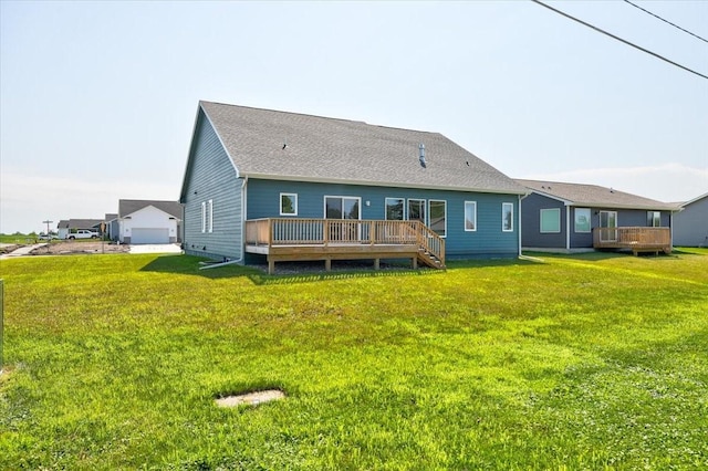 back of house featuring a shingled roof, a lawn, and a wooden deck