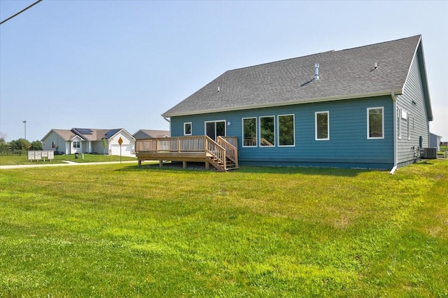 back of property featuring a shingled roof, central AC unit, a deck, and a yard