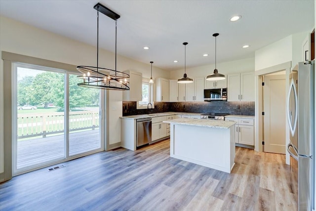 kitchen with stainless steel appliances, a sink, visible vents, and decorative backsplash