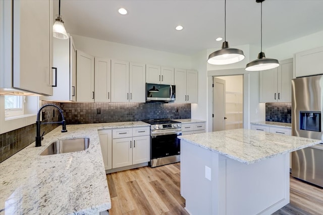 kitchen featuring light stone counters, a center island, light wood finished floors, stainless steel appliances, and a sink