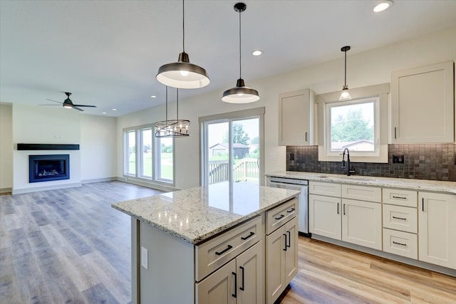 kitchen featuring a center island, a fireplace, backsplash, a sink, and dishwasher