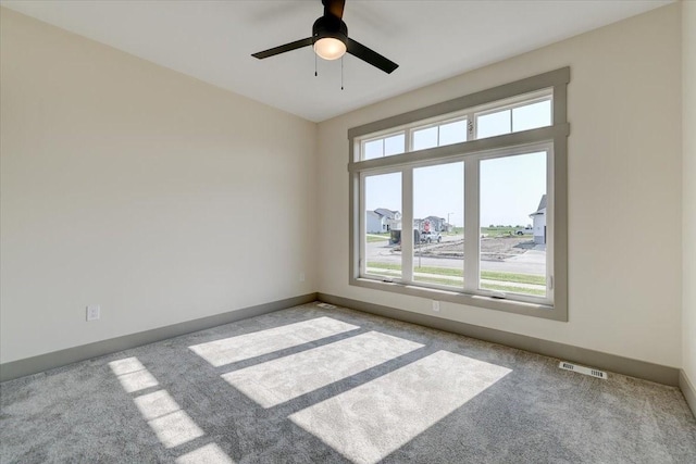 empty room featuring carpet floors, visible vents, and baseboards