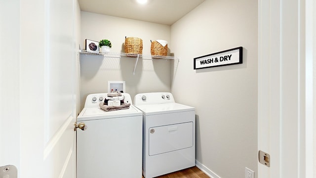 clothes washing area with laundry area, wood finished floors, separate washer and dryer, and baseboards