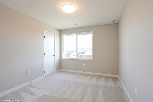 carpeted empty room featuring a textured ceiling